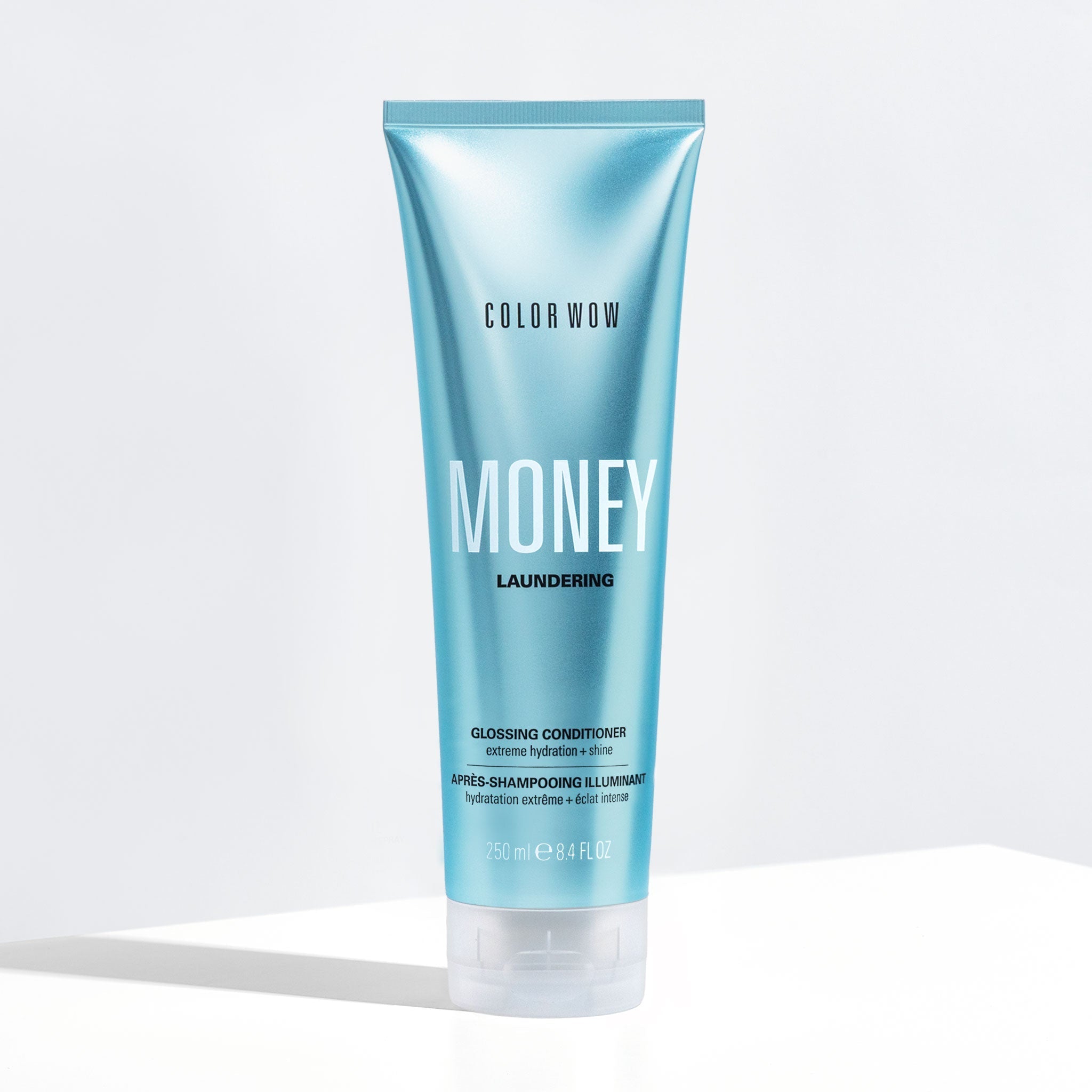 Blue shampoo bottle labeled 'Color Wow Money Laundering Glossing Conditioner' on a white background